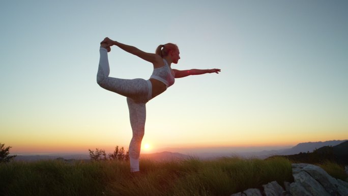 女性在日落前练习瑜伽的姿势。