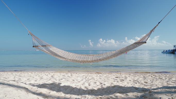 海边热带海滩上棕榈树之间的空吊床