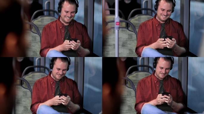 一名男子手持智能手机坐在公交车内