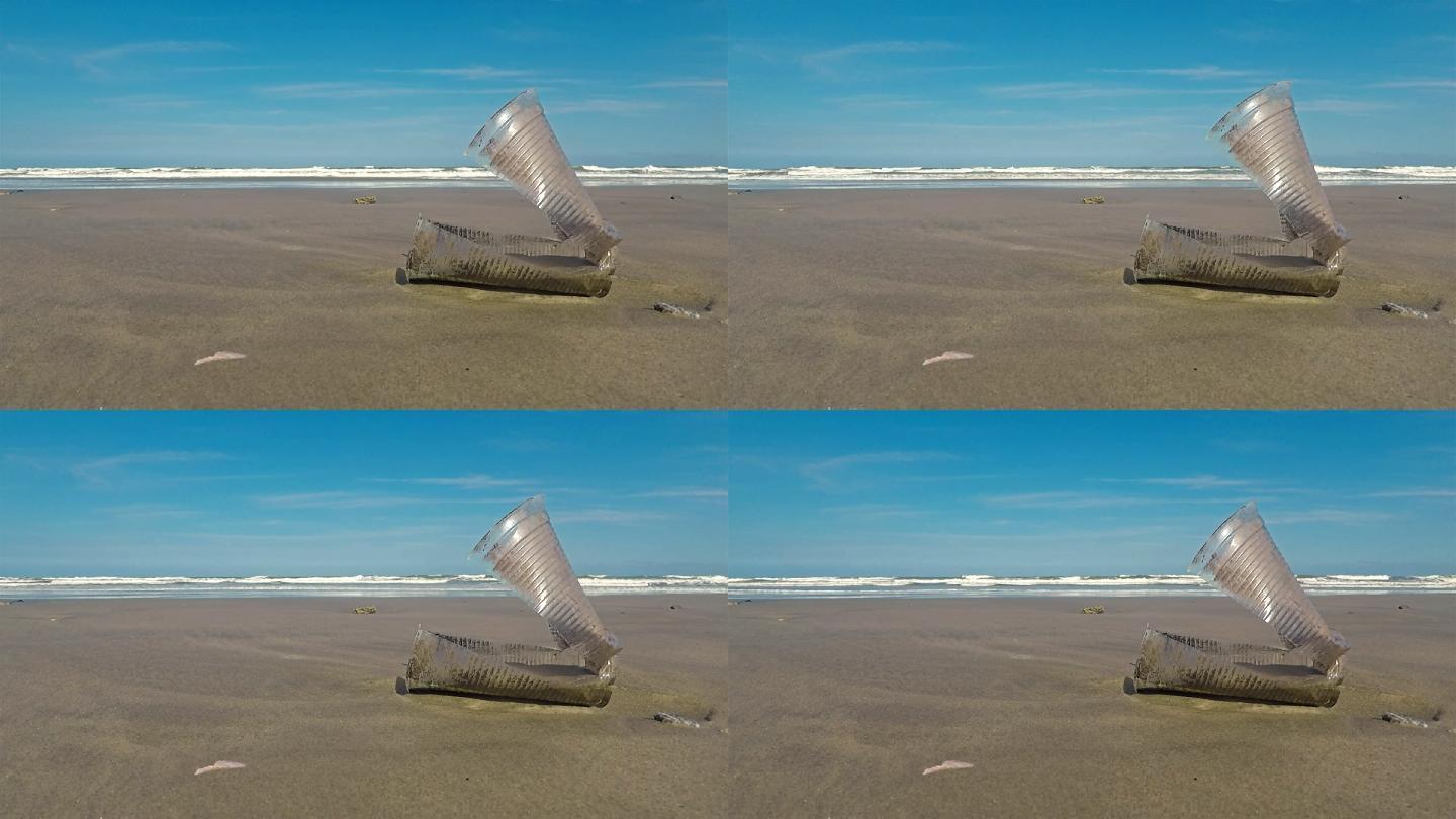 扔在海滩上随风摆动的塑料杯