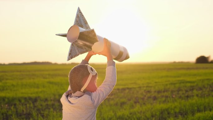 戴着头盔的小男孩在田野里玩火箭
