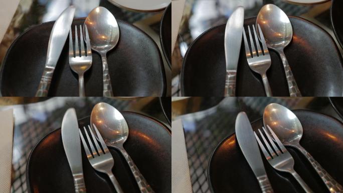 黑色盘子上的勺子、叉子和刀的餐具套装