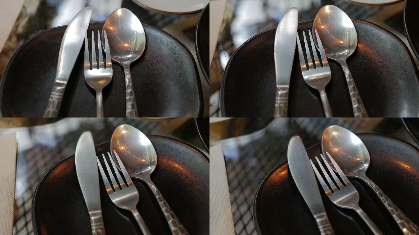 黑色盘子上的勺子、叉子和刀的餐具套装