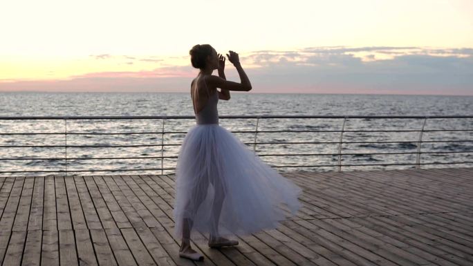 日落时在海堤上锻炼的芭蕾舞演员。