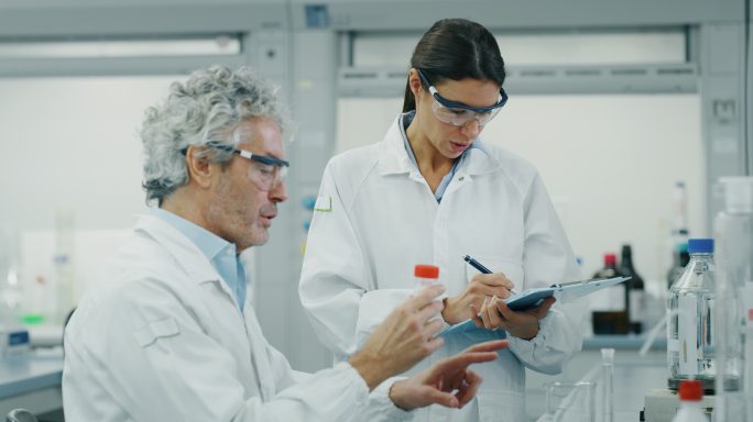两位科学家在实验室测试新药物并签署结果