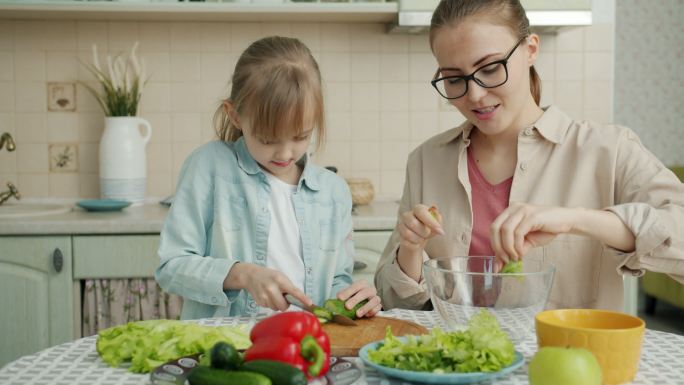小女孩在厨房里帮妈妈切蔬菜做沙拉
