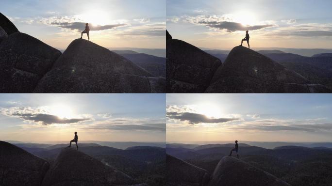 日落时分，一个人站在山顶上的剪影。