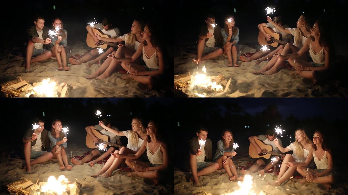 海滩上的朋友们在日落时分拿着火花庆祝