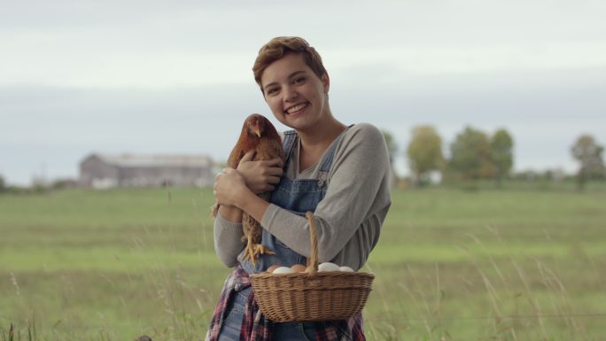 年轻女子在农场里抱着一只宠物鸡