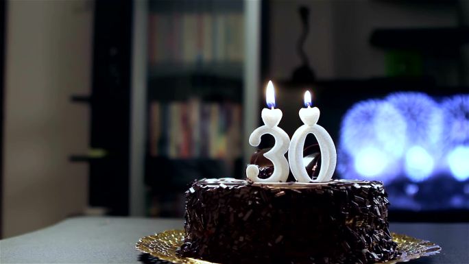 年轻人在他的生日蛋糕上吹蜡烛。