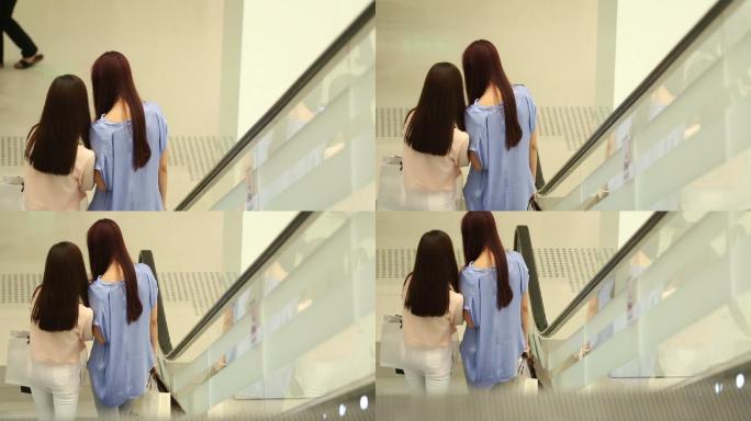 购物中心自动扶梯两位年轻长发女性站立聊天