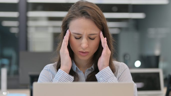 年轻女商人看着笔记本电脑头痛