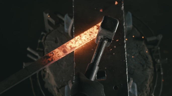 铁匠的双手用锤子敲击炽热的铁板