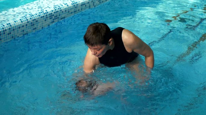 教练教小宝宝在游泳池里游泳