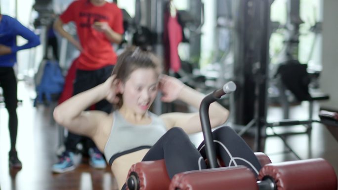 年轻女子在现代健身房仰卧凳腹肌体能训练