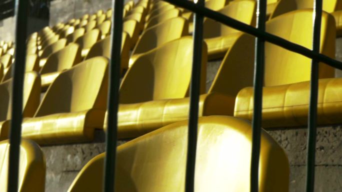 体育场里，金属栅栏后面的黄色椅子