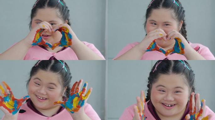 小女孩面带微笑，展示用颜料画的手。