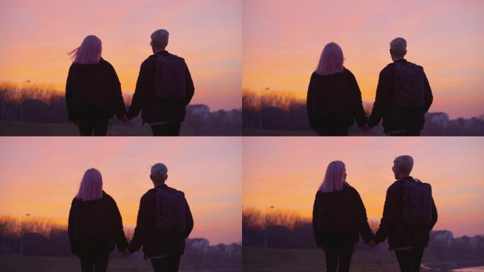 十几岁的情侣手牵手在河边欣赏着日落