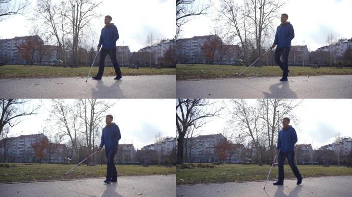 残疾的年轻男性用手杖在公园散步