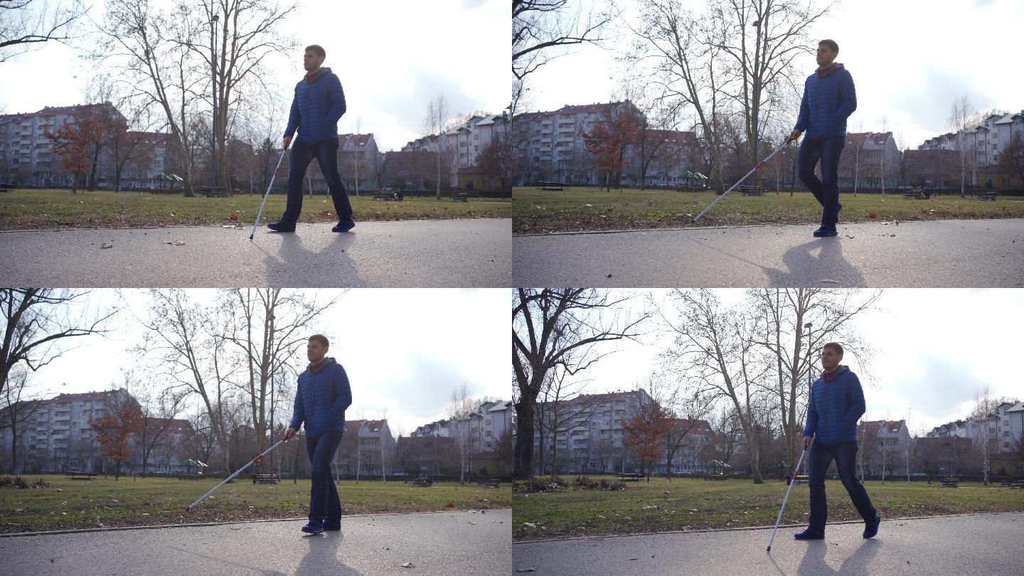 残疾的年轻男性用手杖在公园散步