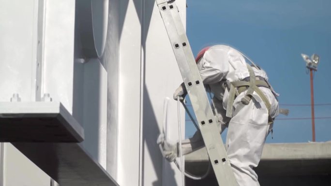 穿着防护服的工人在建筑结构上涂上涂料。