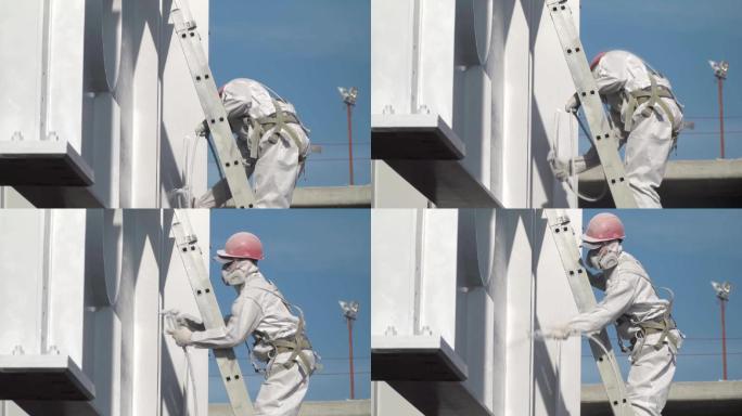 穿着防护服的工人在建筑结构上涂上涂料。