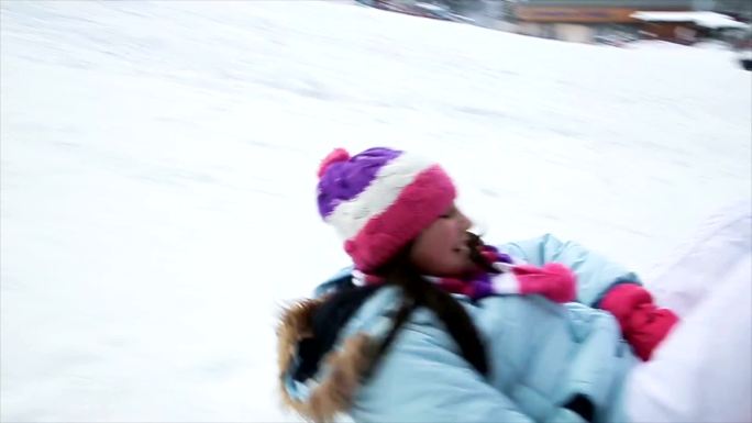 母亲和女儿在冬季滑雪中心玩雪橇