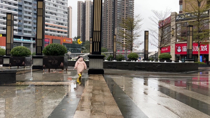 雨后在小区门口广场踩水玩水的小女孩