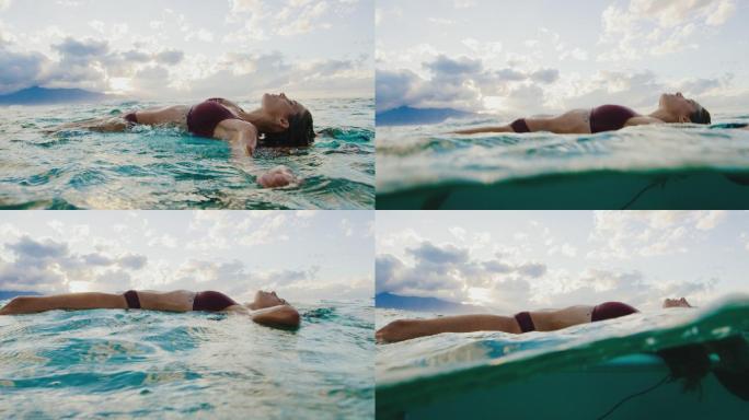 美丽的冲浪女孩在日落时在海洋中放松