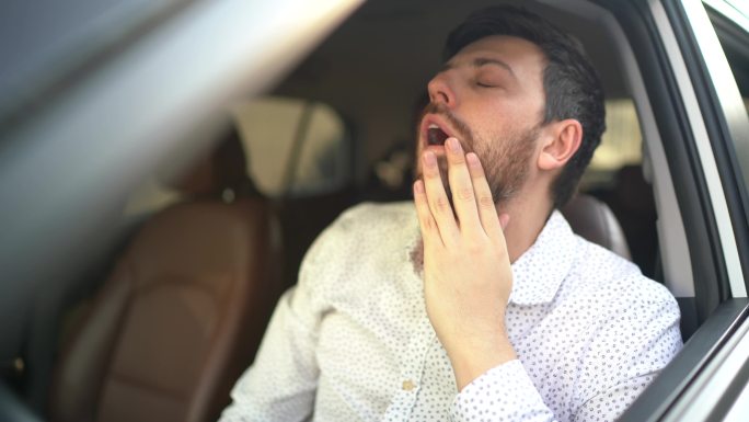 焦虑的司机开车的男子晨光中捂脸抚脸犯困