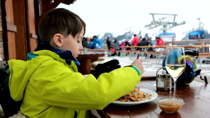 男孩在阳光明媚的冬日滑雪场欣赏风景