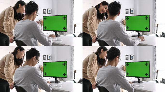 两个人看着绿色屏幕的电脑