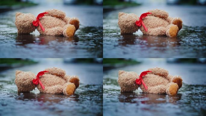 被遗弃的小熊躺在潮湿的路上