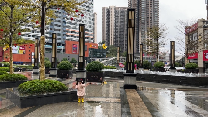 雨后在小区门口广场跳水坑踩水玩水的小女孩