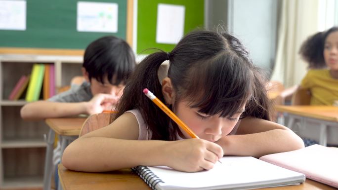 女学生坐在学校里用铅笔写字