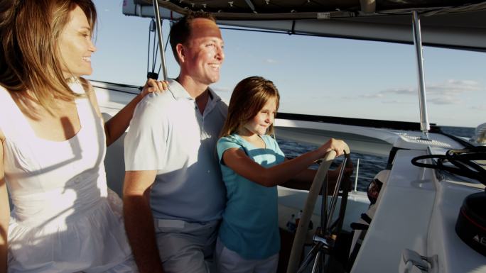 年轻的父母和女儿一起开游艇