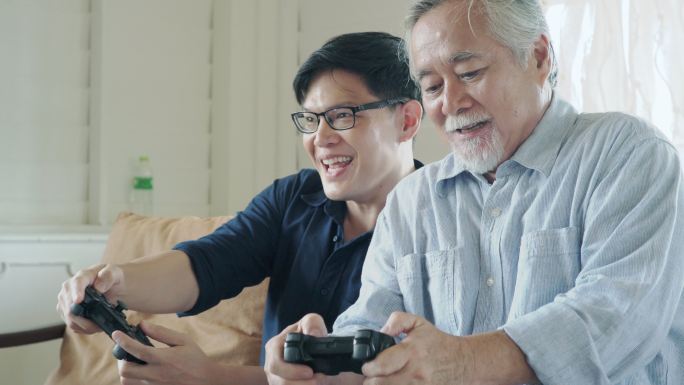 年长的父亲和他儿子喜欢一起玩电子游戏。