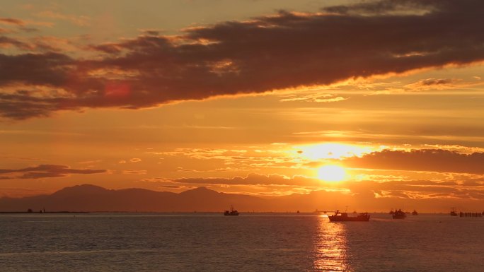 美丽的夕阳黄昏海上渔船出海打渔剪影云层海