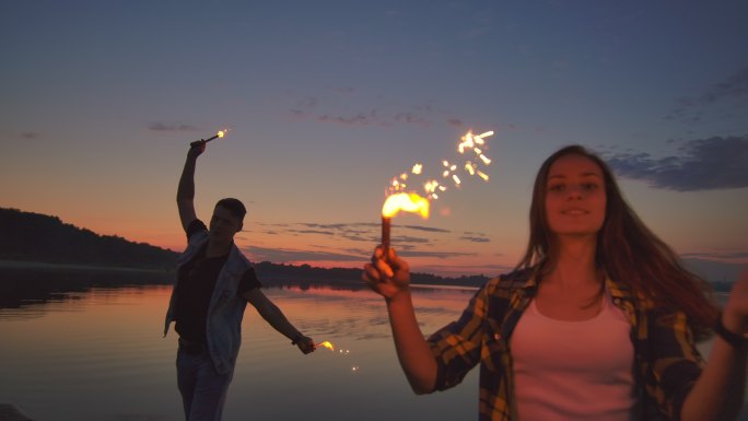年轻夫妇手持燃烧着的闪闪发光的火花