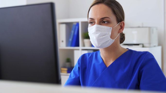 戴着口罩的医生在医院使用电脑