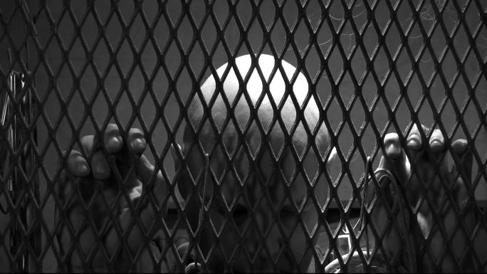 一个被锁在金属笼子里的男人
