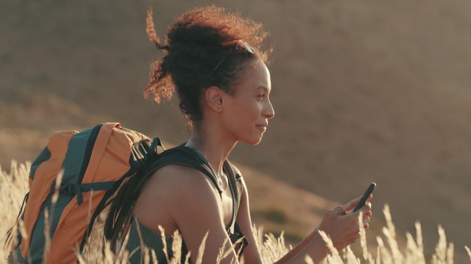 一名年轻女子徒步旅行时使用手机