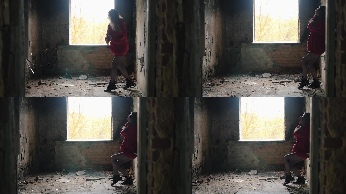 悲伤的小女孩正向一栋废弃建筑的墙上扔相框