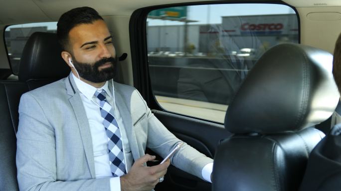 商人在豪华轿车中使用智能手机