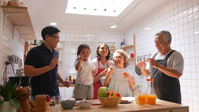 多代家庭一起在厨房做饭和跳舞。