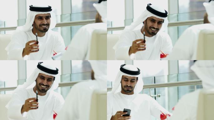 穿着民族服装的阿拉伯商人在使用手机