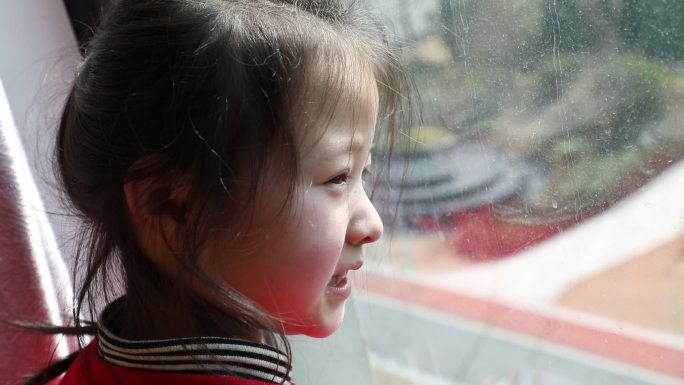小女孩看向窗外开心的样子