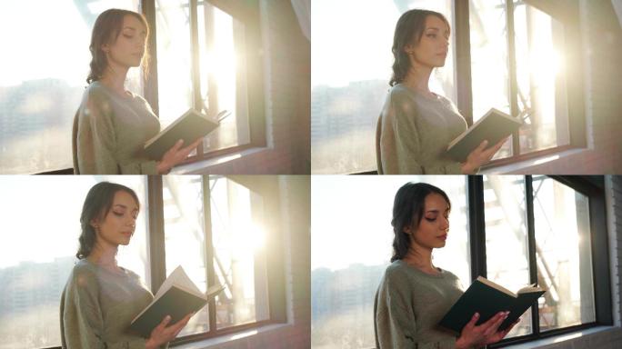 女人站在窗边，在日落的背景下看书