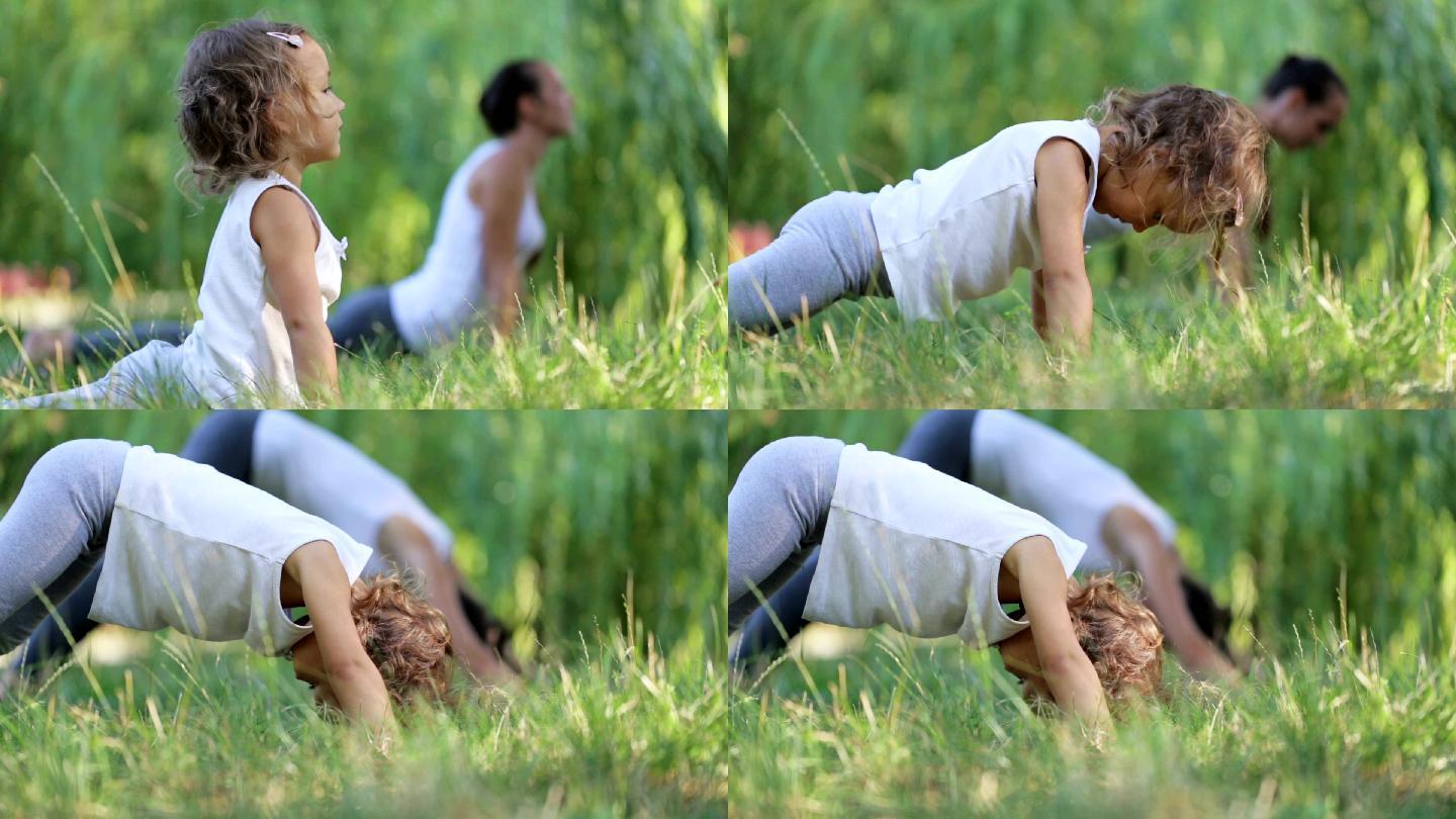 妈妈和女儿在一个绿色的公园里晨练瑜伽
