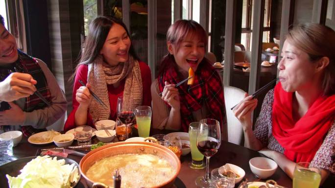 快乐的年轻朋友们在火锅餐厅享用晚餐